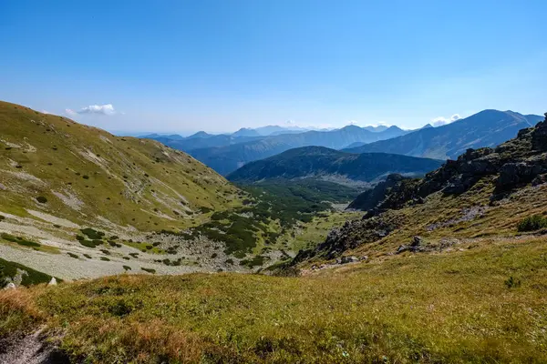 rocky mountain tops with hiking trails in autumn in Slovakian Tatra western Carpathian with blue sky and late grass on  hills. Empty rocks in bright daylight, far horizon for adventures.