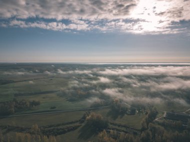 drone görüntü. hava alanları ve ormanları ile kırsal alan görünümünü sonbahar sis kaplı. Letonya - vintage eski film bakmak