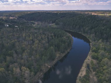 drone görüntü. alanları ve ormanları ve bulutlu bahar günü nehir su yansımalar kırsal alan hava görünümünü. Letonya - vintage eski film bakmak