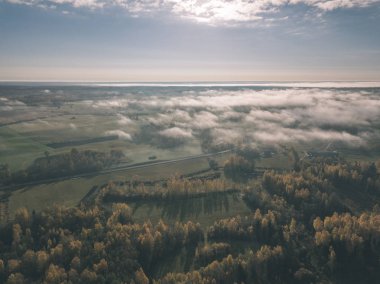 drone görüntü. hava alanları ve ormanları ile kırsal alan görünümünü sonbahar sis kaplı. Letonya - vintage eski film bakmak