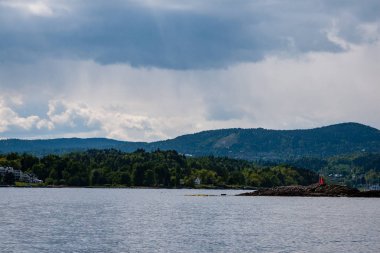 güzel kayalık sahil şeridine Norveç'te sakin su mavi gökyüzü altında