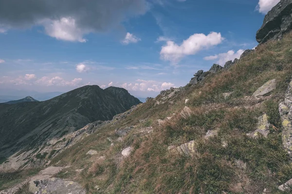 beautiful rocky mountain tops with hiking trails in autumn in Slovakian Tatra western Carpathian mountains with blue sky and late grass on hills. Empty rocks in bright daylight, far horizon for adventures