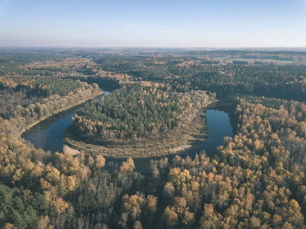 drone image. aerial view of wavy river in autumn colored forest. latvia, river of gauja - vintage old film look