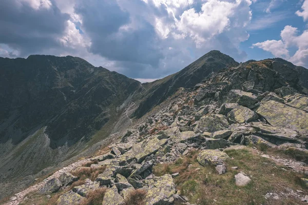 beautiful rocky mountain tops with hiking trails in autumn in Slovakian Tatra western Carpathian mountains with blue sky and late grass on hills. Empty rocks in bright daylight, far horizon for adventures