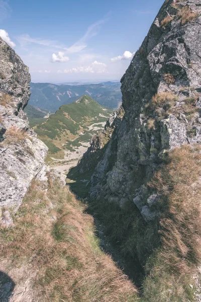 beautiful rocky mountain tops with hiking trails in autumn in Slovakian Tatra western Carpathian mountains with blue sky and late grass on hills. Empty rocks in bright daylight, far horizon for adventures