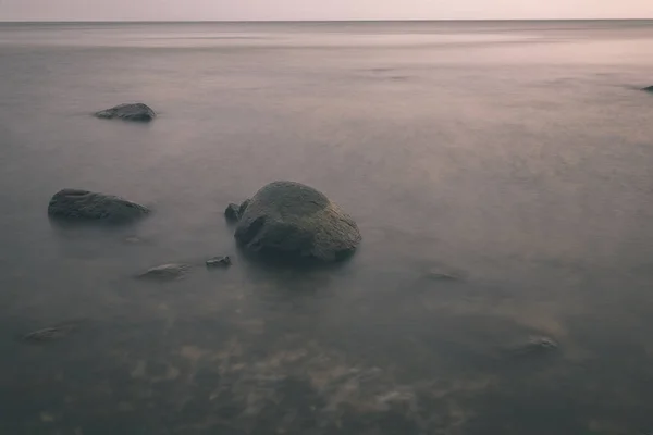 長時間露光海は岩のビーチや洗浄水の波 テクスチャの抽象画像 ヴィンテージの古い映画に見える — ストック写真