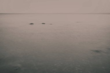 uzun pozlama deniz kaya ile plaj ve su dalgalar yıkanmış. vintage eski film dokulu soyut resim - bak