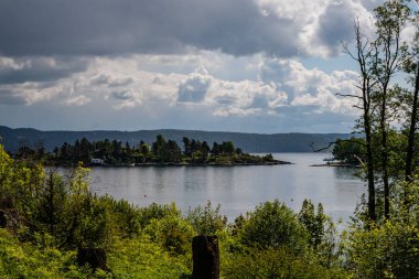 kayalık sahil şeridine Norveç'te kaç çam ağaçları ve mavi gökyüzü altında sakin su