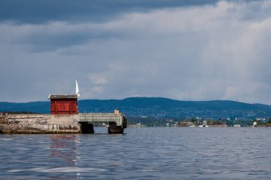 kayalık sahil şeridine Norveç'te kaç çam ağaçları ve mavi gökyüzü altında sakin su
