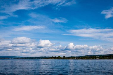 güzel kayalık sahil şeridine Norveç'te sakin su mavi gökyüzü altında