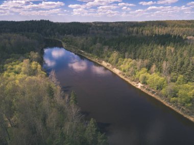 drone görüntü. alanları ve ormanları ve bulutlu bahar günü nehir su yansımalar kırsal alan hava görünümünü. Letonya - vintage eski film bakmak