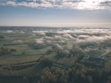 drone görüntü. hava alanları ve ormanları ile kırsal alan görünümünü sonbahar sis kaplı. Letonya - vintage eski film bakmak
