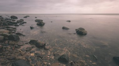 uzun pozlama deniz kaya ile plaj ve su dalgalar yıkanmış. vintage eski film dokulu soyut resim - bak