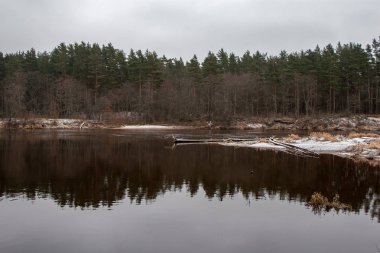 nehir, Gauja Valmiera yakınındaki kumtaşı kayalıklarla ve erken kış sakin su ile. çıplak ağaçlar