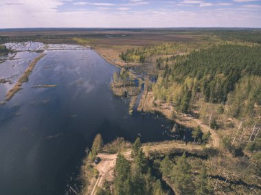 drone görüntü. alanları ve ormanları ve bulutlu bahar günü nehir su yansımalar kırsal alan hava görünümünü. Letonya - vintage eski film bakmak