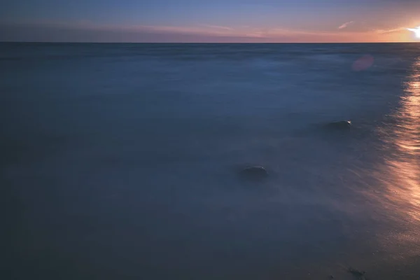 長時間露光海は岩のビーチや洗浄水の波 テクスチャの抽象画像 ヴィンテージの古い映画に見える — ストック写真