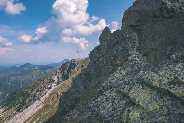 beautiful rocky mountain tops with hiking trails in autumn in Slovakian Tatra western Carpathian mountains with blue sky and late grass on hills. Empty rocks in bright daylight, far horizon for adventures