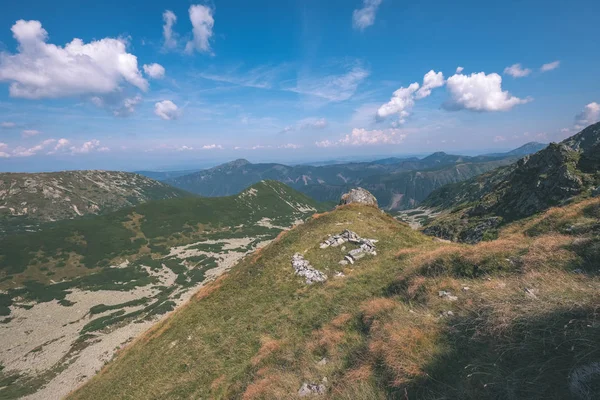 beautiful rocky mountain tops with hiking trails in autumn in Slovakian Tatra western Carpathian mountains with blue sky and late grass on hills. Empty rocks in bright daylight, far horizon for adventures