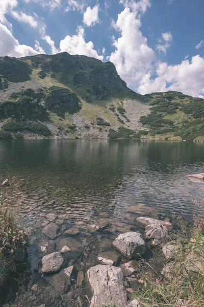 mountain lake panorama view in late summer in Slovakian Carpathian Tatra with reflections of rocky hills in water. Rohacske plesa lakes near Zverovka village. - vintage old film look