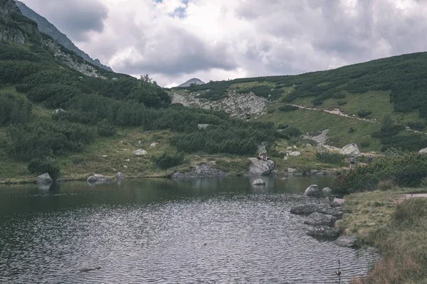 mountain lake panorama view in late summer in Slovakian Carpathian Tatra with reflections of rocky hills in water. Rohacske plesa lakes near Zverovka village. - vintage old film look