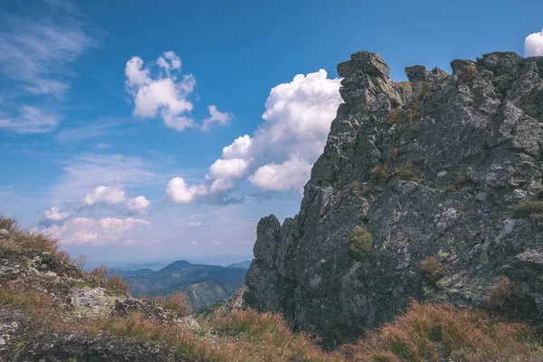 beautiful rocky mountain tops with hiking trails in autumn in Slovakian Tatra western Carpathian mountains with blue sky and late grass on hills. Empty rocks in bright daylight, far horizon for adventures