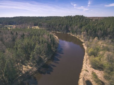 drone görüntü. alanları ve ormanları ve bulutlu bahar günü nehir su yansımalar kırsal alan hava görünümünü. Letonya - vintage eski film bakmak