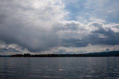güzel kayalık sahil şeridine Norveç'te sakin su mavi gökyüzü altında