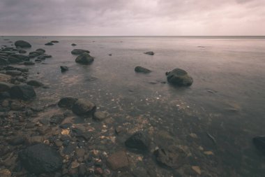uzun pozlama deniz kaya ile plaj ve su dalgalar yıkanmış. vintage eski film dokulu soyut resim - bak