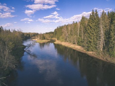 drone görüntü. alanları ve ormanları ve bulutlu bahar günü nehir su yansımalar kırsal alan hava görünümünü. Letonya - vintage eski film bakmak