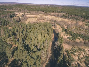 drone görüntü. alanları ve ormanları ve bulutlu bahar günü nehir su yansımalar kırsal alan hava görünümünü. Letonya - vintage eski film bakmak