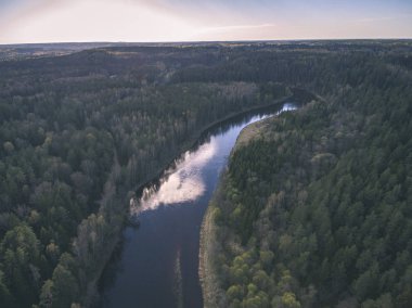 drone görüntü. alanları ve ormanları ve bulutlu bahar günü nehir su yansımalar kırsal alan hava görünümünü. Letonya - vintage eski film bakmak