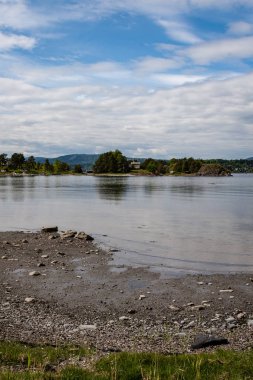 güzel kayalık sahil şeridine Norveç'te sakin su mavi gökyüzü altında