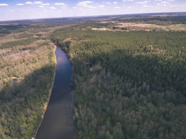 drone görüntü. alanları ve ormanları ve bulutlu bahar günü nehir su yansımalar kırsal alan hava görünümünü. Letonya - vintage eski film bakmak