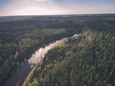 drone görüntü. alanları ve ormanları ve bulutlu bahar günü nehir su yansımalar kırsal alan hava görünümünü. Letonya - vintage eski film bakmak