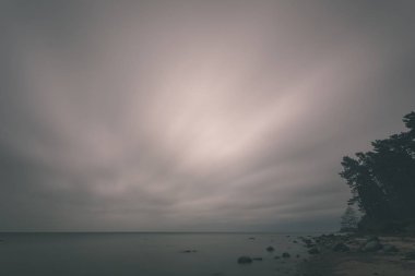 uzun pozlama deniz kaya ile plaj ve su dalgalar yıkanmış. vintage eski film dokulu soyut resim - bak