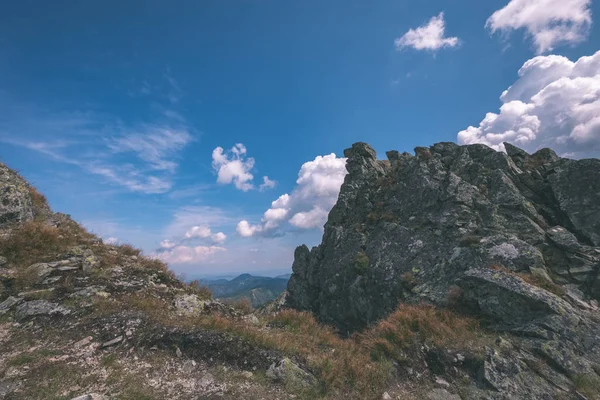 beautiful rocky mountain tops with hiking trails in autumn in Slovakian Tatra western Carpathian mountains with blue sky and late grass on hills. Empty rocks in bright daylight, far horizon for adventures