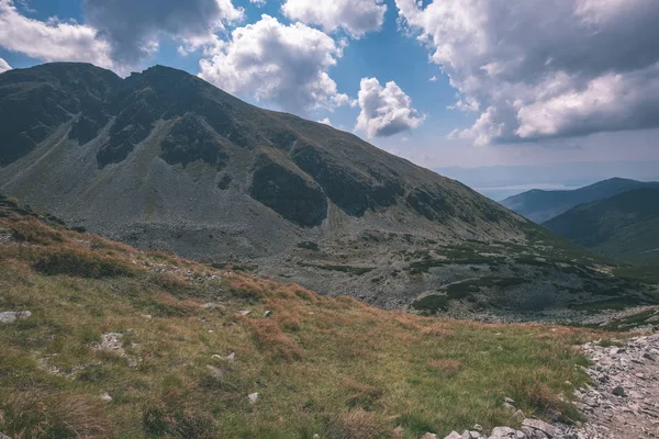rocky mountain tops with hiking trails in autumn in Slovakian Tatra western Carpathian with blue sky and late grass on  hills. Empty rocks in bright daylight, far horizon for adventures. - vintage old film look
