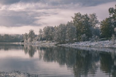 soğuk ve sakin sabah görünümü ile ilk gölün vintage bir retro görünüm sol - yeşil yaprakları ile Kışın kar