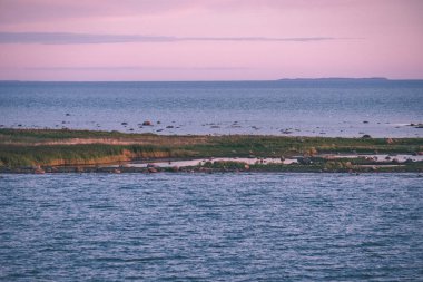 panoramik deniz plaj manzarası içinde kaya, bitkiler ve temiz su ile yaz aylarında güneşli bir gün