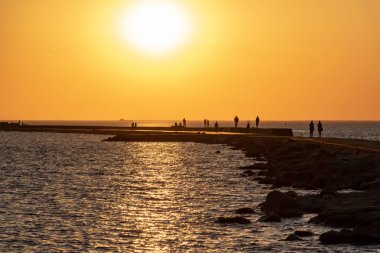 dalgakıran deniz günbatımı insanlar tarafından yürüyüş sonunda kırmızı deniz feneri ile