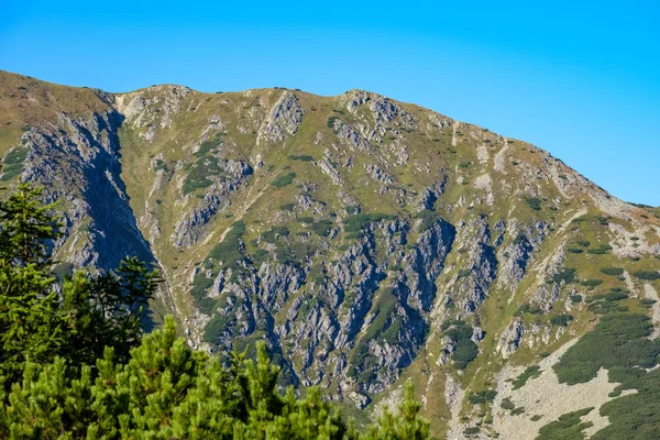 Distant mountain cores in mist in slovakia Tatra mountain trails in clear autumn day with blue sky and green vegetation