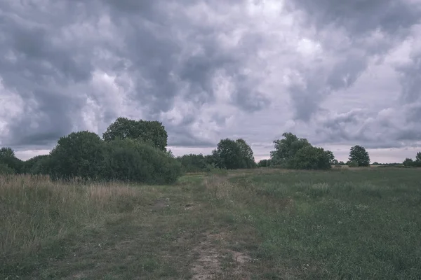 storm clouds forming over the countryside and fields with roads - vintage retro look