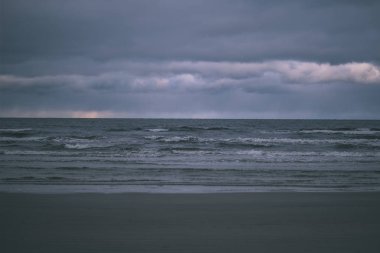 deniz üzerinde fırtına bulutları. temiz beyaz kum plaj üzerinde küçük dalgalar. sığ derinlik-in tarla - vintage bir retro görünüm