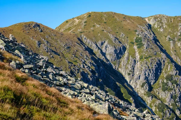 Distant mountain cores in mist in slovakia Tatra mountain trails in clear autumn day with blue sky and green vegetation