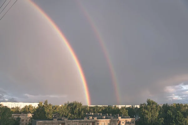 Dark storm clouds over city with rainbow and electricity wires