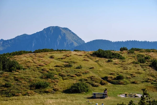 Distant mountain cores in mist in slovakia Tatra mountain trails in clear autumn day with blue sky and green vegetation