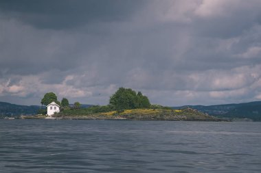 kayalık sahil şeridine Norveç'te kaç çam ağaçları ve mavi gökyüzü - vintage bir retro görünüm altında sakin su