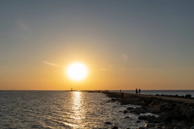 dalgakıran deniz günbatımı insanlar tarafından yürüyüş sonunda kırmızı deniz feneri ile