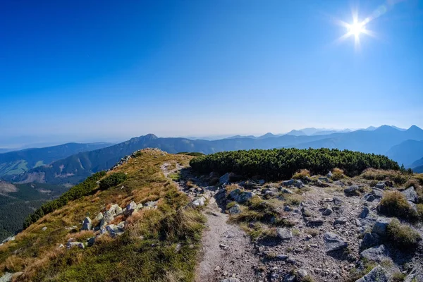 Distant mountain cores in mist in slovakia Tatra mountain trails in clear autumn day with blue sky and green vegetation