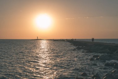 dalgakıran deniz günbatımı insanlar tarafından - vintage bir retro görünüm ile sonunda kırmızı deniz feneri ile